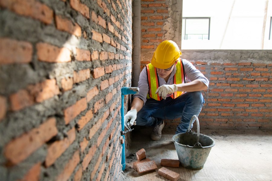 Foto van bouwvakker die een muur voegt